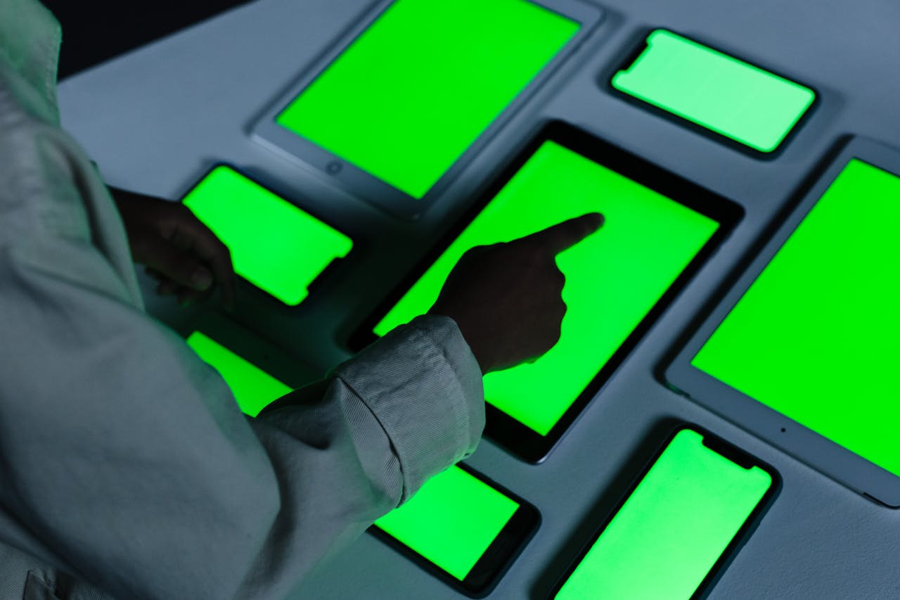 home-img Person interacting with multiple green-screen electronic devices indoors.